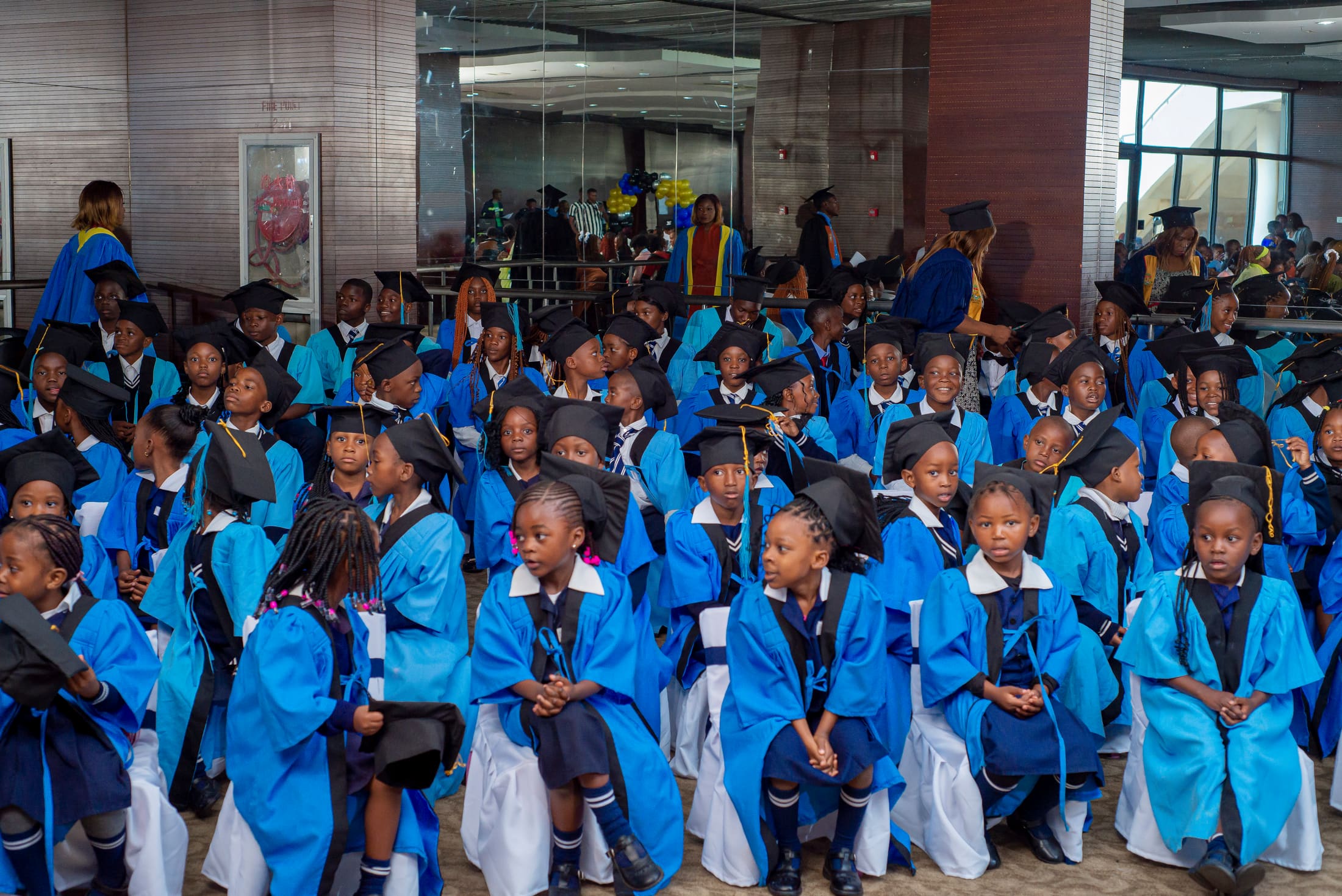 Tukiya pupils seated in blue graduation gowns and caps